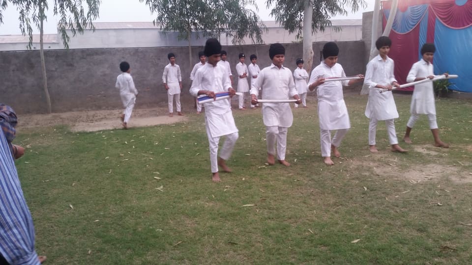 A line of students practising Gatka drills together on the grass
