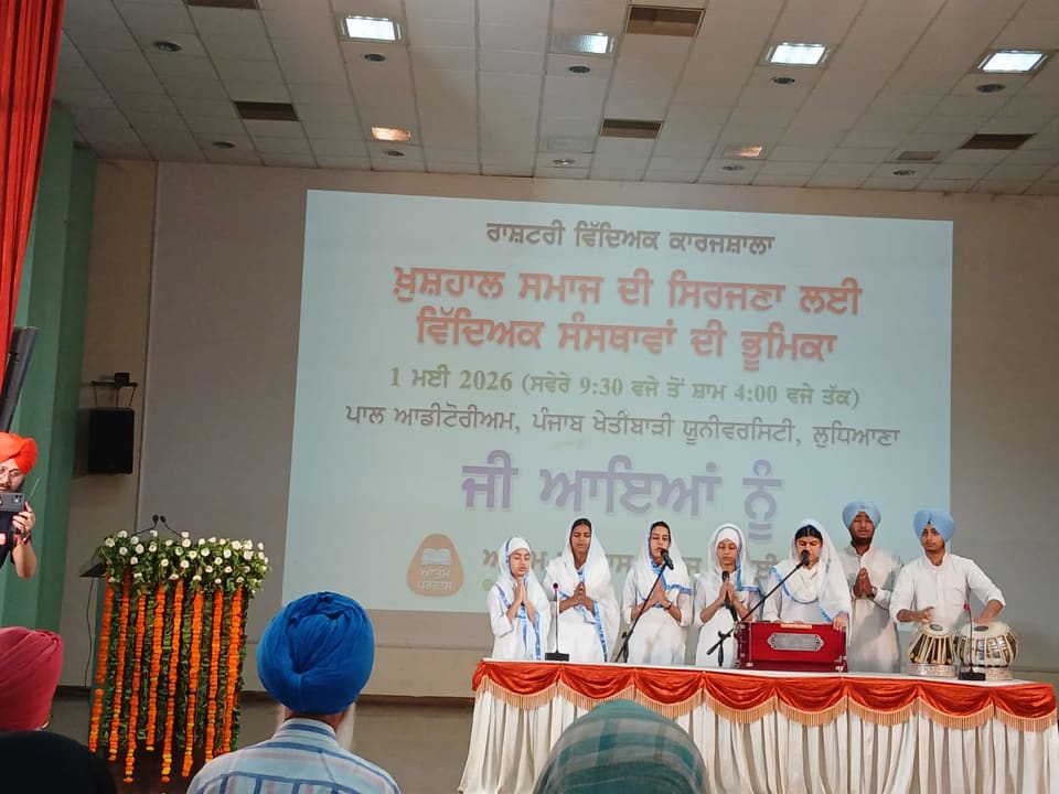 Seminar stage with dignitaries and a Punjabi-language presentation screen