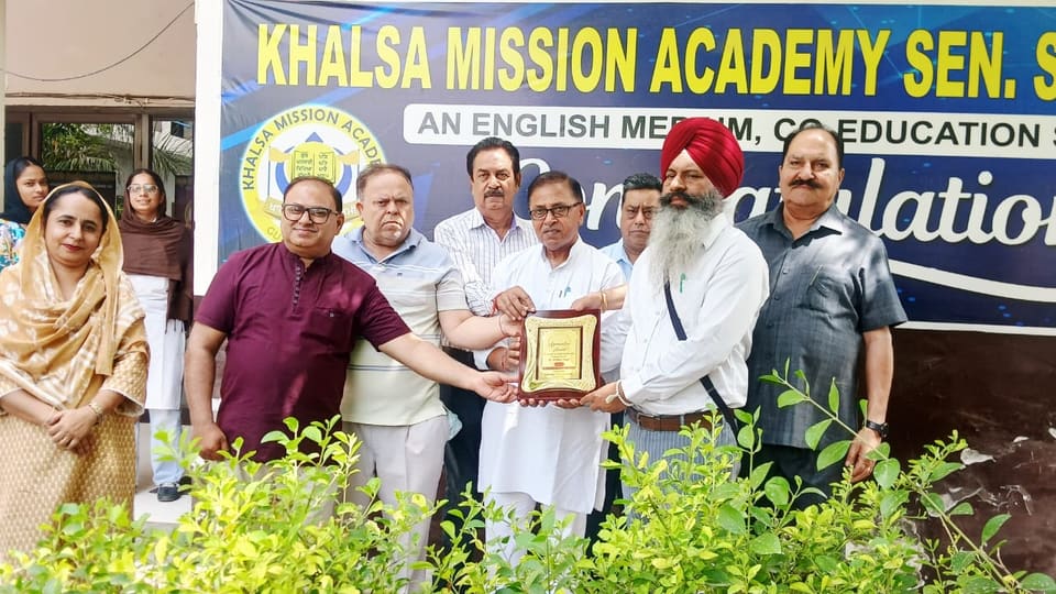 Staff and guests at a congratulations ceremony under the school banner