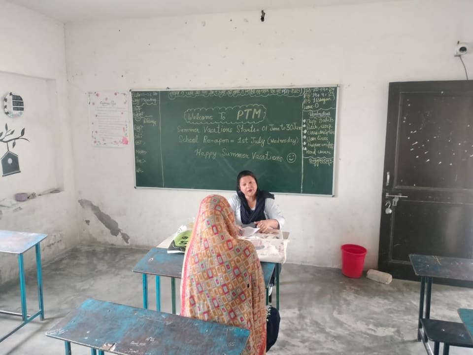 Classroom prepared for the parent-teacher meeting with a teacher at the desk