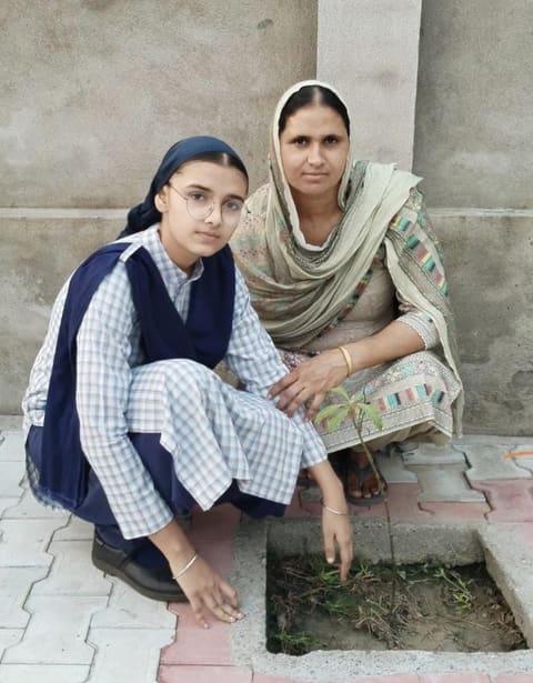 A student tending a newly planted sapling with a family member