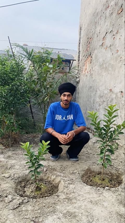A student seated between two newly planted saplings