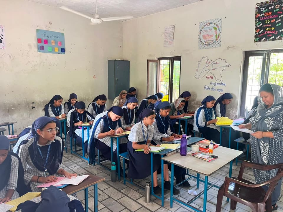 Senior students writing in their notebooks with a teacher nearby