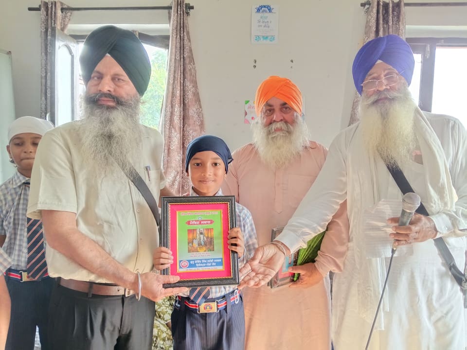 A young student receiving a framed award from community elders