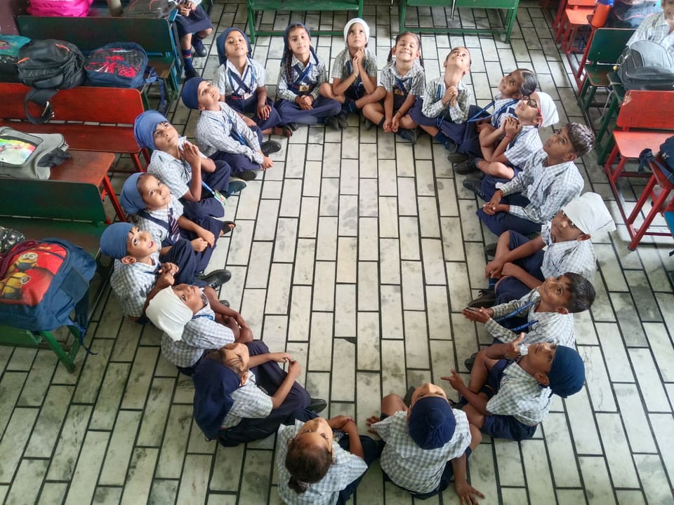 Young students seated in a large circle on the classroom floor