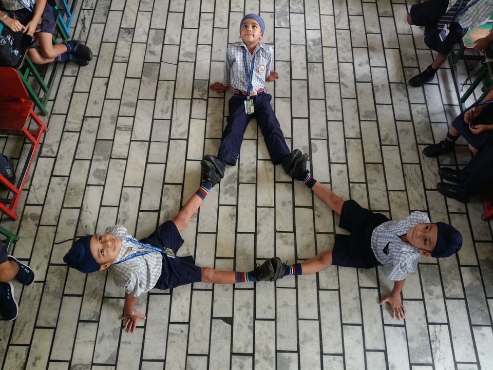 A student demonstrating a gymnastics split on the classroom floor