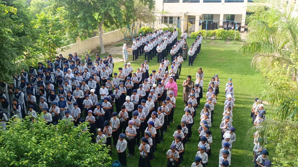 Students at assembly framed by trees and lawns on campus