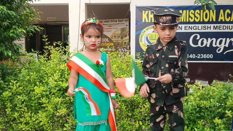 Two students in fancy dress in front of the school banner