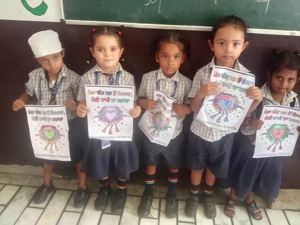 Young students holding their coloured Raksha Bandhan drawings