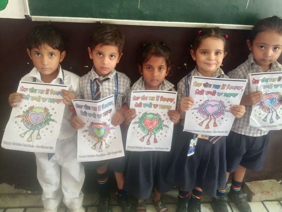 Children displaying hand-coloured Rakhi posters in class
