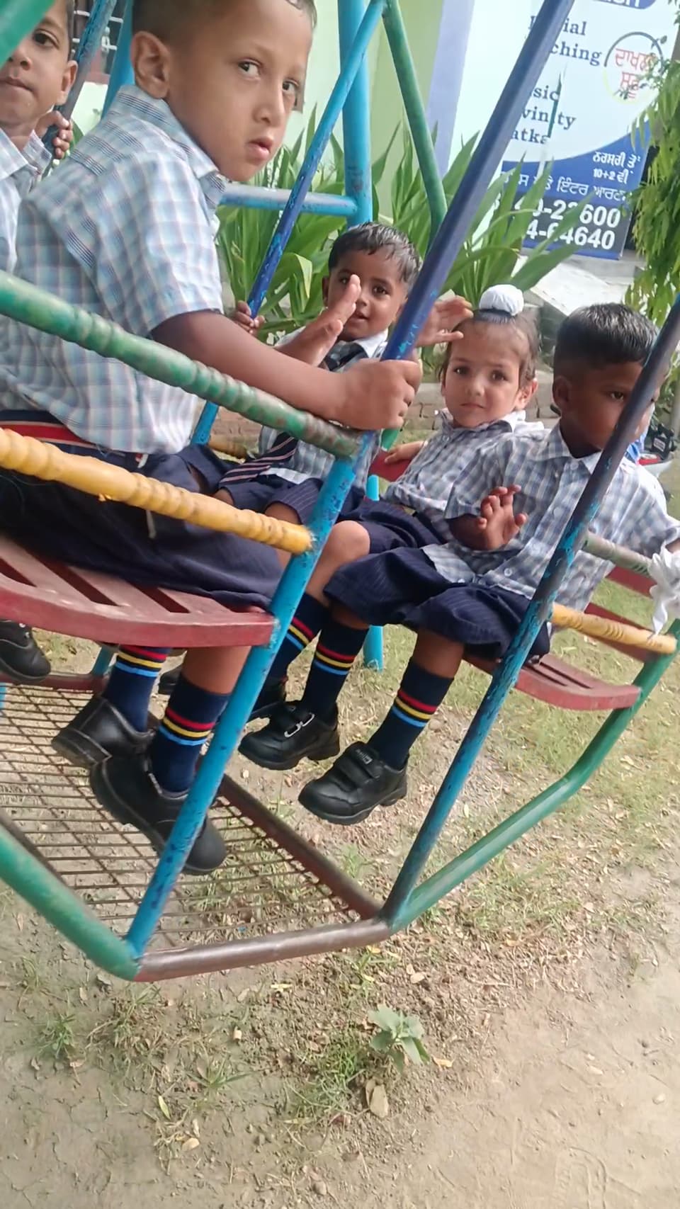 Young students playing on the swings in the school play area