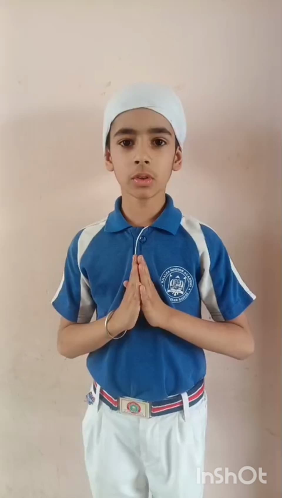 A student standing with folded hands reciting before the school