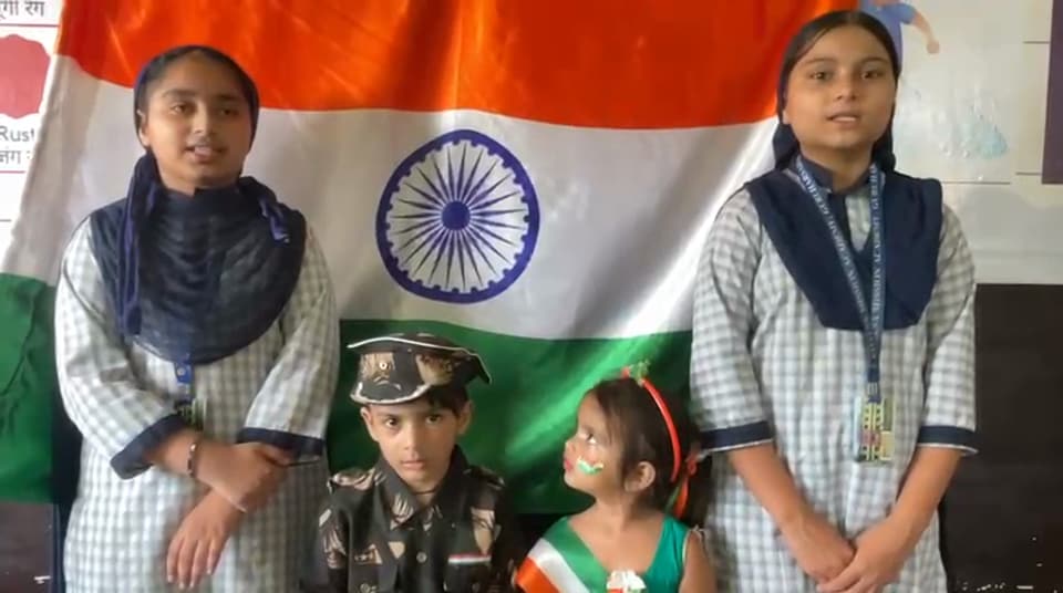 Students and fancy-dress juniors performing in front of the national flag