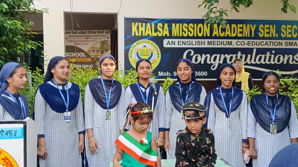 Students and fancy-dress juniors in front of the school banner
