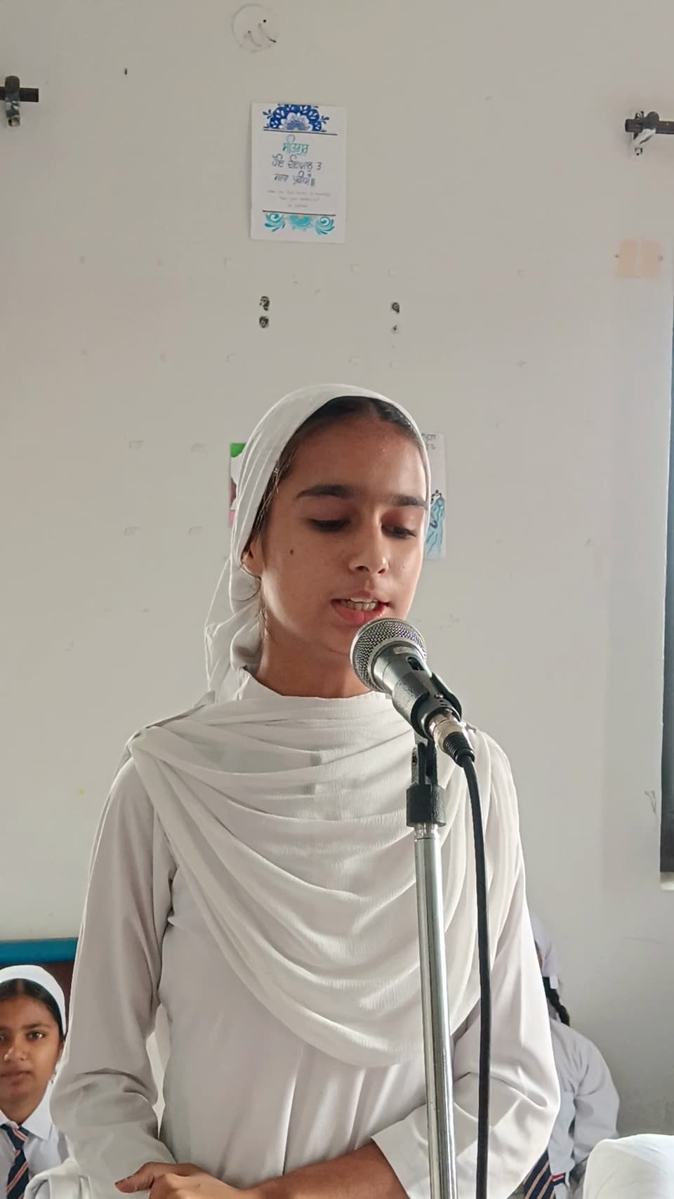 A student singing a shabad at the assembly microphone