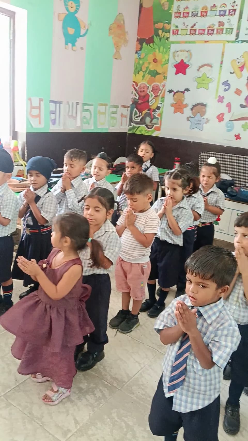 Nursery students clapping together in a brightly decorated classroom